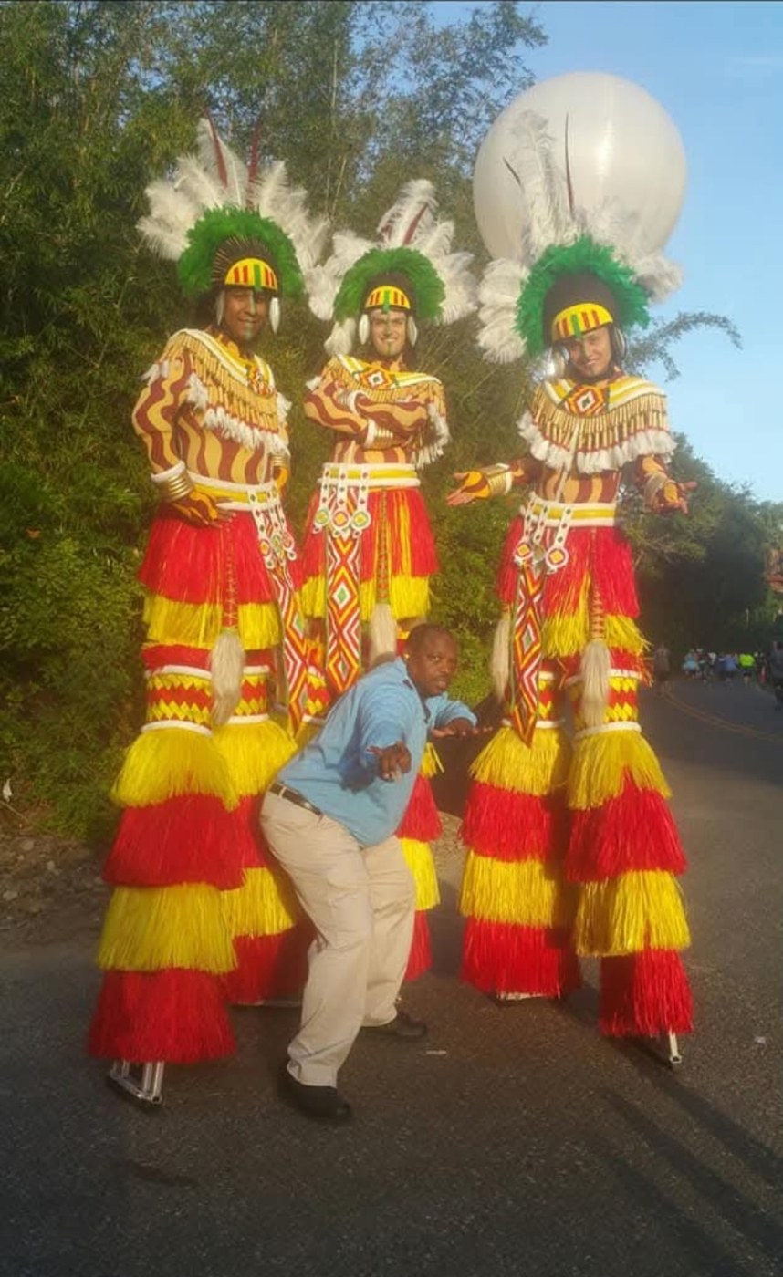 Will with island stilt dancers in colorful costumes